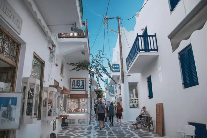 Rue pavée typique en Grèce avec maisons blanches et volets bleus, évoquant le décalage horaire Grèce dans un cadre de voyage